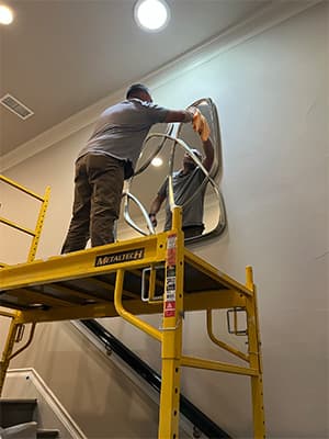 man on ladder cleaning mirror